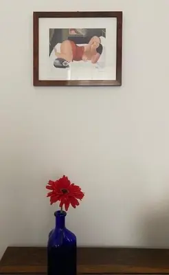 a blue vase with a red flower in front of a picture at Civico 18 in Rome