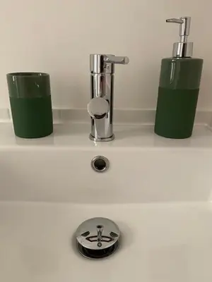 a bathroom sink with two green containers on a counter at Civico 18 in Rome