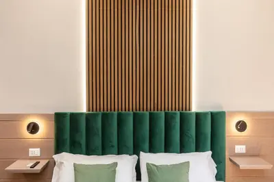 a bedroom with a green headboard and white pillows at Iron Monti Coliseum in Rome
