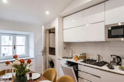 a kitchen with white cabinets and a table with flowers at The Best Rent - Refined multi-room apartment in Termini area in Rome