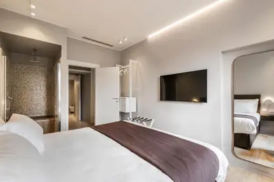 a bedroom with a large white bed and a tv at Trastevere Travertino Suite in Rome