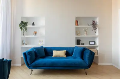a blue couch in a living room with white shelves at iFlat La Dolce Vita - Contemporary Luxury in Rome in Rome