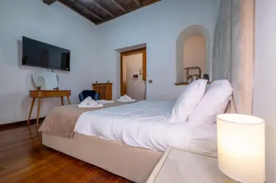a bedroom with a large white bed with a flat screen tv at Trevi Guesthouse in Rome
