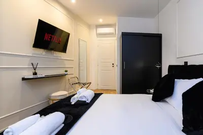 a bedroom with a bed with white sheets and a tv at Rome Elegant Suite in Rome