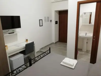 a bathroom with a sink and a desk with a television at Grandis Rooms in Rome