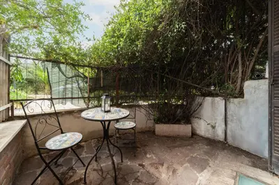 a patio with a table and two chairs and a tree at GuestHost - Comfy Apartment near Vatican City! in Rome
