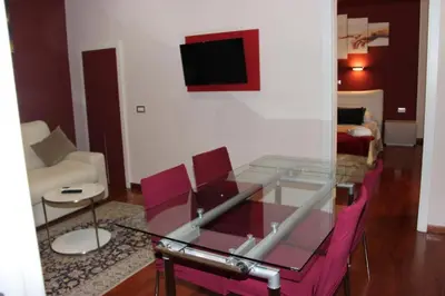 a living room with a glass table and pink chairs at Dimora Frattina in Rome