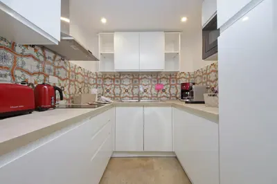 a kitchen with white cabinets and a tile wall at MM Trevi Apartment in Rome