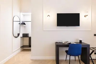 a desk with a blue chair and a television on a wall at Piazza del Popolo Boutique GuestHouse in Rome