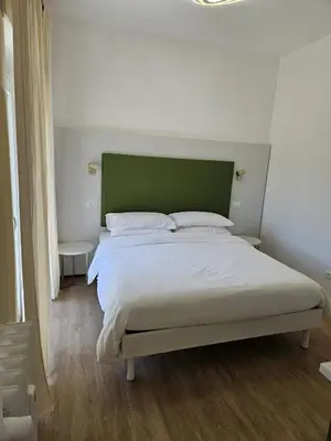a bedroom with a large bed with a green headboard at Toto San Paolo Rooms in Rome
