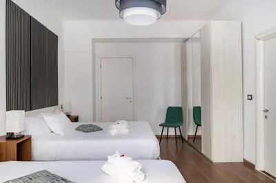 two beds in a room with two green chairs at Vatican Dimora Apartments in Rome