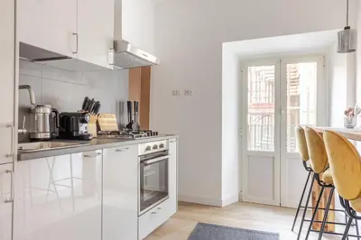 a kitchen with white appliances and a table with stools at Piazza di Spagna 2 Bedrooms and 5 Juliet Balcony in Rome