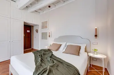 a white bedroom with a white bed and a table at Romantic Studio with Balcony near Navona Square in Rome
