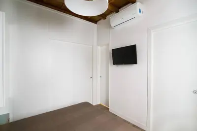 a room with a white wall with a flat screen tv at Domenichino Luxury Home in Rome
