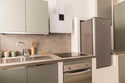a kitchen with white cabinets and a stainless steel refrigerator at Comfort Suite Balduina - Rome in Rome
