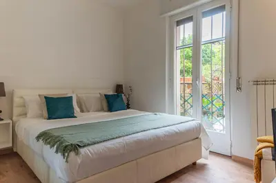 a white bedroom with a large bed with blue pillows at San Pietro Il Campanile in Rome