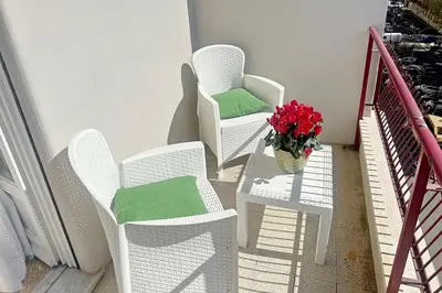 three white chairs and a vase of flowers on a balcony at Domus 68 - Apartment with terrace in Rome