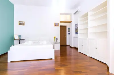 a white bedroom with a white bed and a wooden floor at Elegantis Veniero Suite Apartment - 1 Minute Walk to Vatican Museums in Rome