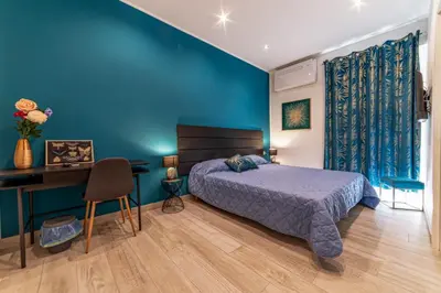 a bedroom with blue walls and a bed and a desk at Michelangelo Luxury Rooms - Colosseo - WiFi in Rome