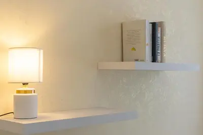 a white shelf with a lamp and books on it at Nel Cuore di Testaccio by Rental in Rome in Rome