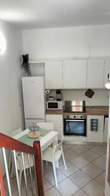 a kitchen with white cabinets and a table and a stove at Stefy's House Appio Tuscolano in Rome