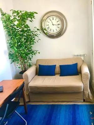 a couch with two blue pillows in a living room with a clock at San Peter-Vatican Way in Rome
