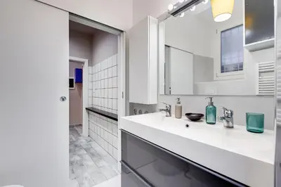 a white bathroom with a sink and a mirror at LuxurySistersHouse 2 min Colosseum in Rome