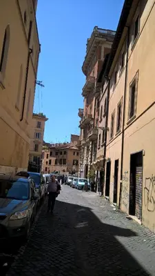 a person walking down a street next to buildings at Around The Corner Colosseo B&B in Rome