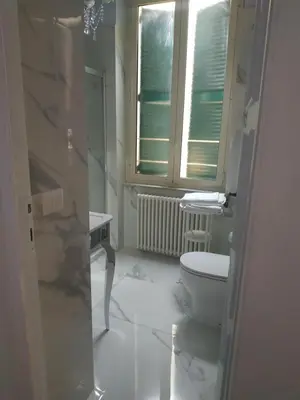 a white bathroom with a toilet and a window at Around The Corner Colosseo B&B in Rome