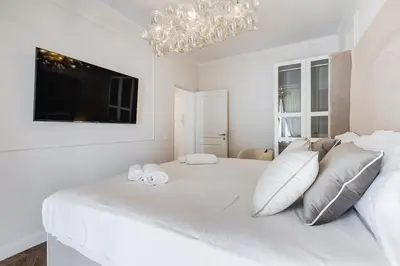 a white bedroom with a large white bed with a chandelier at Vatican Design Apartment - NEW! in Rome