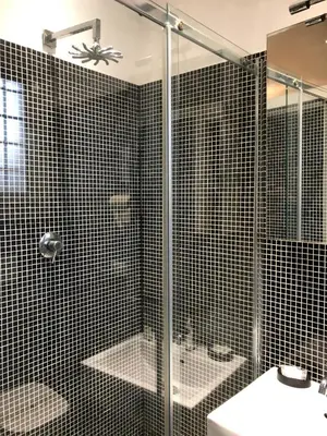 a black tiled bathroom with a shower and a sink at Rhome Lungotevere River in Rome