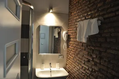 a bathroom with a sink and a brick wall at Imperial Relais in Rome