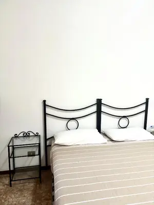 a bed with a black frame and a side table at Casa Rita 15 minuti dal centro in Rome