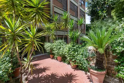 a garden with palm trees and plants in front of a building at ROMAN DREAM lV in Rome