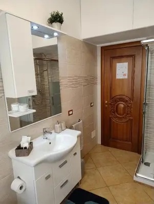 a bathroom with a sink and a mirror and a door at Alcinque - Casa vacanze in Rome