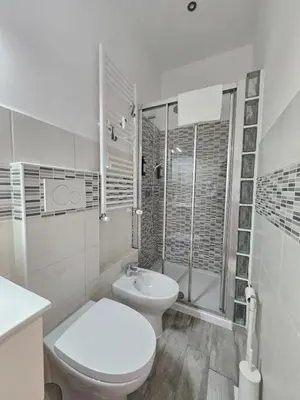 a white bathroom with a toilet and a shower at San Lorenzo Garden Suites in Rome