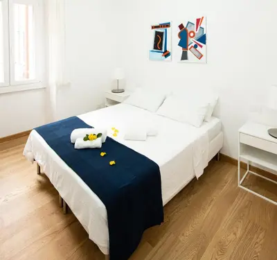 a white bedroom with a bed with a blue blanket at Domus Aurea a stone's throw from the Colosseum in Rome