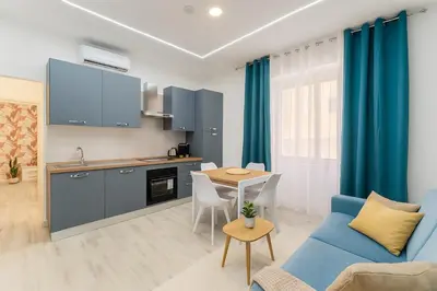 a kitchen and living room with a blue couch and a table at Jhonny's Apartment Near Vatican 3 bedroom's in Rome