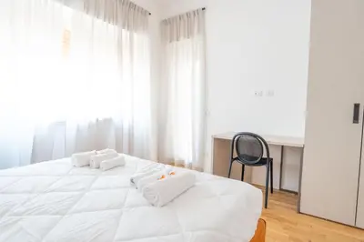 a white bedroom with a large white bed and a chair at Home d'élite Gregory in Rome