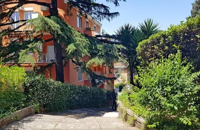 an orange building with trees and bushes next to a sidewalk at San Pietro in Vaticano Terrazza Giovy in Rome