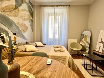 a room with two beds and a table in it at Archouse - Elegant apartment a 10 min dal Colosseo in Rome