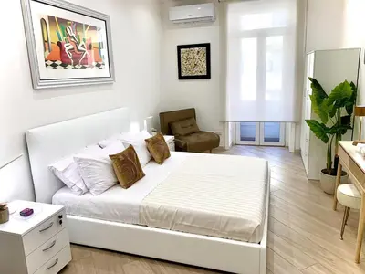 a white bedroom with a bed and a chair at Appartamento metro Ponte Lungo in Rome
