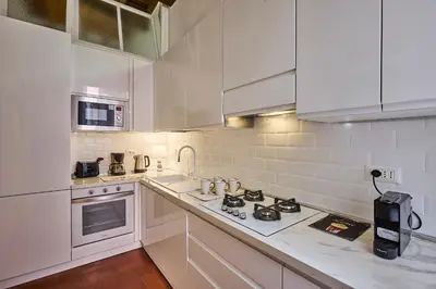 a kitchen with white cabinets and a stove top oven at Navona Maison in Rome