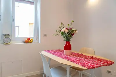 a table with a red vase with flowers on it at 18 Vatican Penthouse in Rome