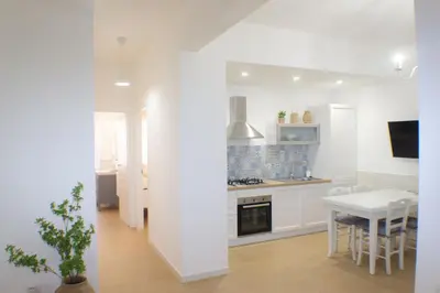 a white kitchen with a table and a dining room at Armonia Mediterranea Apartments in Rome