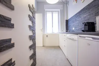 a kitchen with white cabinets and a brick wall at Royal House Vaticano in Rome