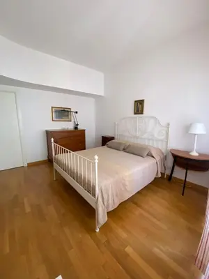 a bedroom with a white bed and a wooden floor at Nina House Roma in Rome