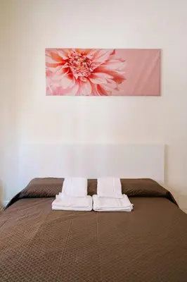 a bed with two towels and a painting on the wall at Marilyn Rooms in Rome