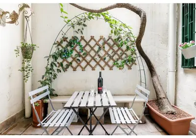 a table and chairs on a patio with a trellis at RHOMENJOY Pied-à-terre Colosseo in Rome