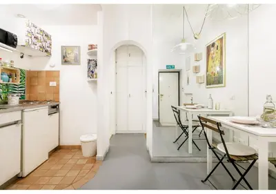 a white kitchen with a table and chairs at RHOMENJOY Pied-à-terre Colosseo in Rome